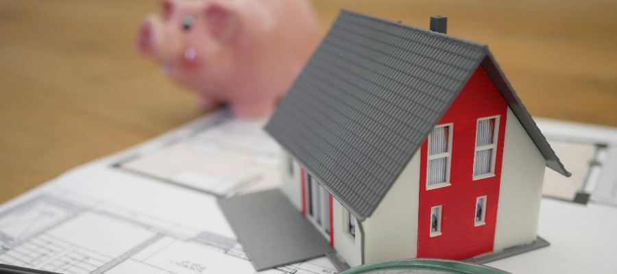 Un pequeño modelo de casa con una alcancía al fondo