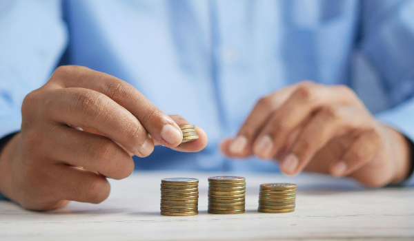 Una persona con tres grupos de monedas apiladas