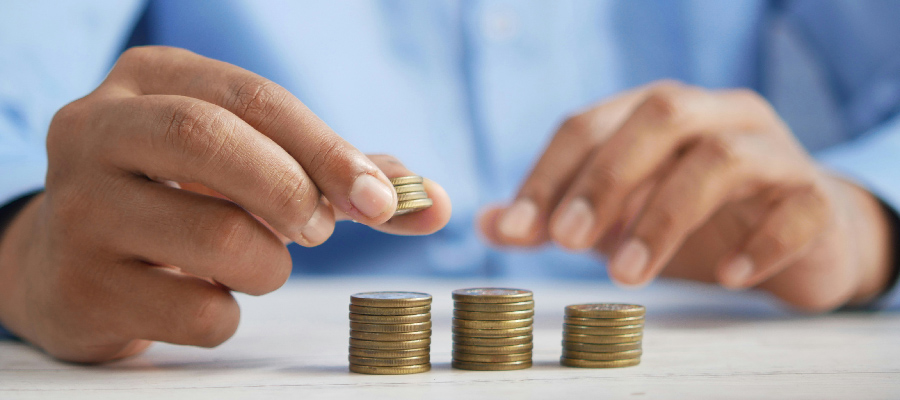 Una persona con tres grupos de monedas apiladas